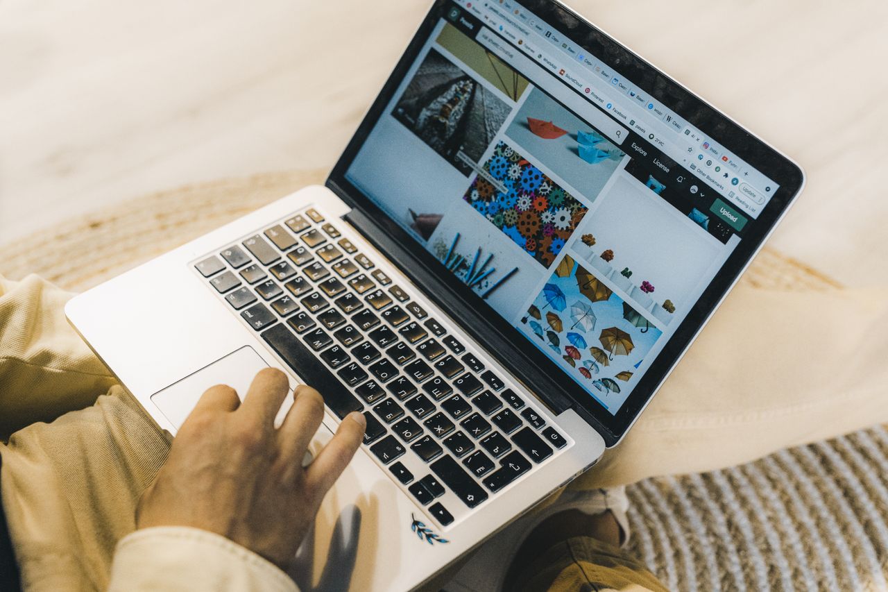 A person using a laptop to browse stock photo websites, working freelance in a comfortable setting.