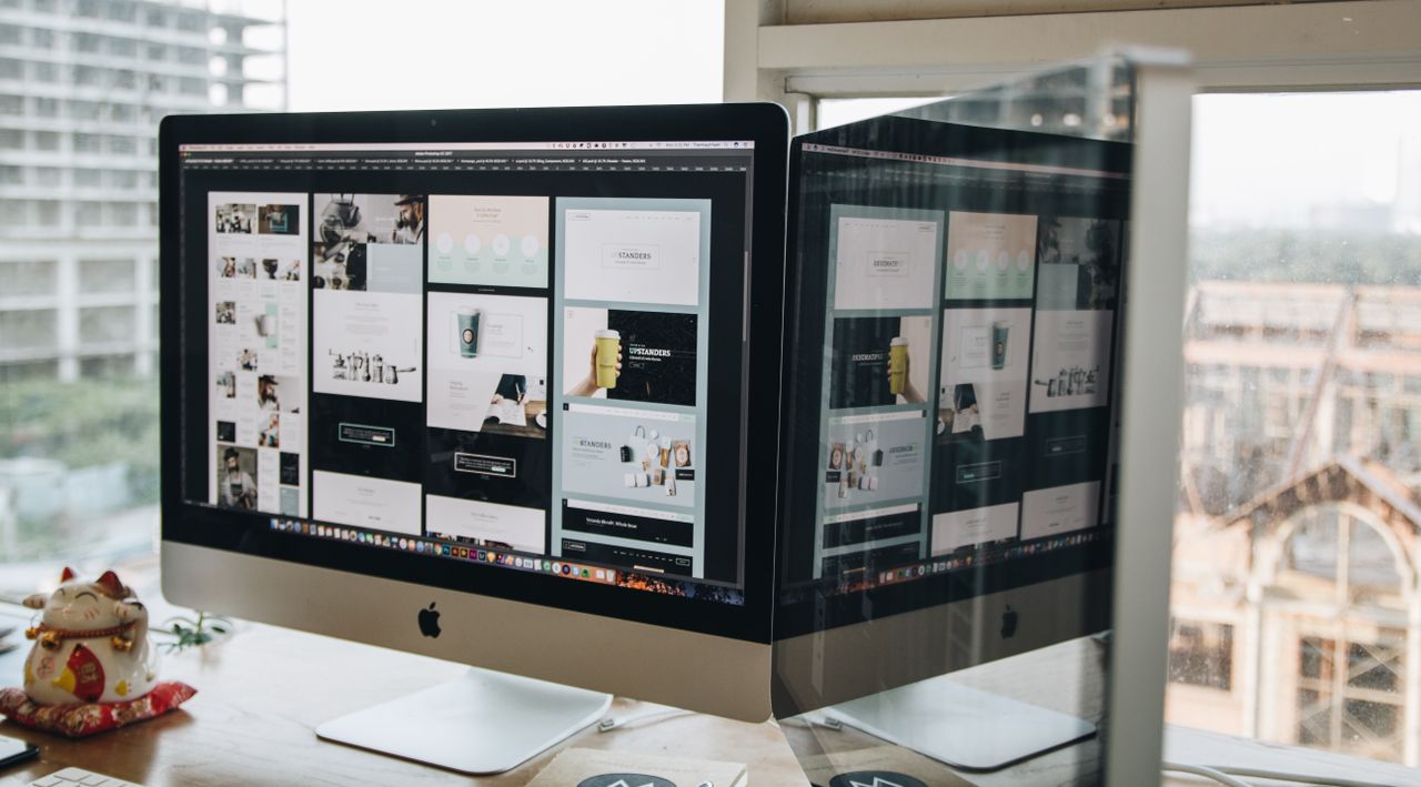 Due monitor su una scrivania, che mostrano un progetto web in un ambiente d’ufficio contemporaneo.